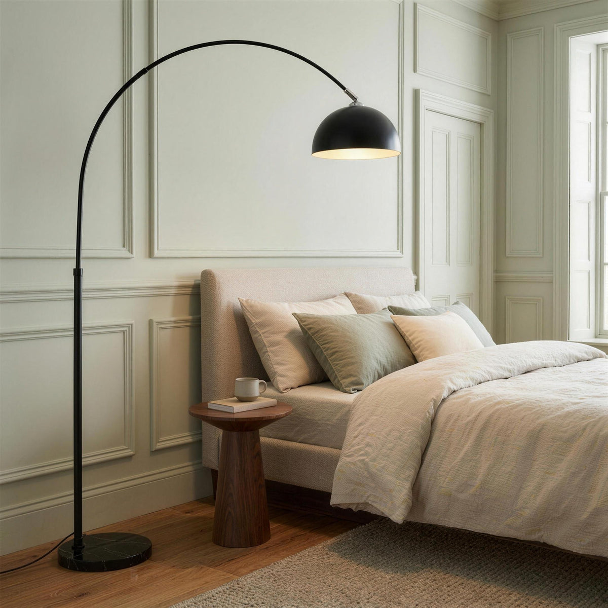 Black arc floor lamp with marble base in a bright bedroom