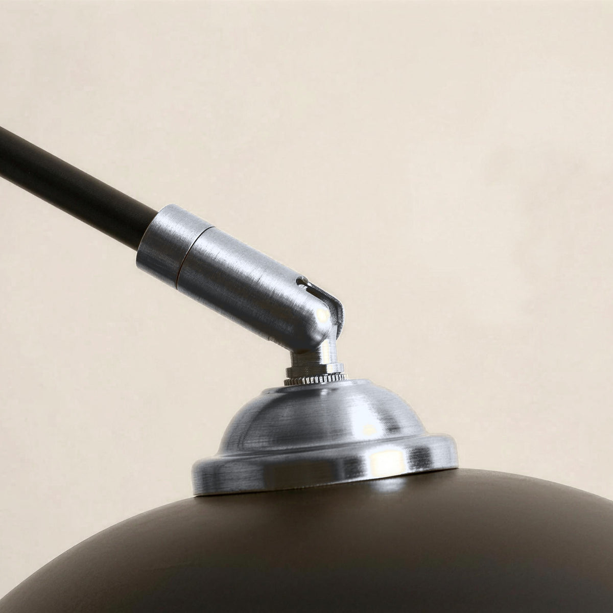 Close-up of the chrome-finish joint and dome cap on a black arc floor lamp shade