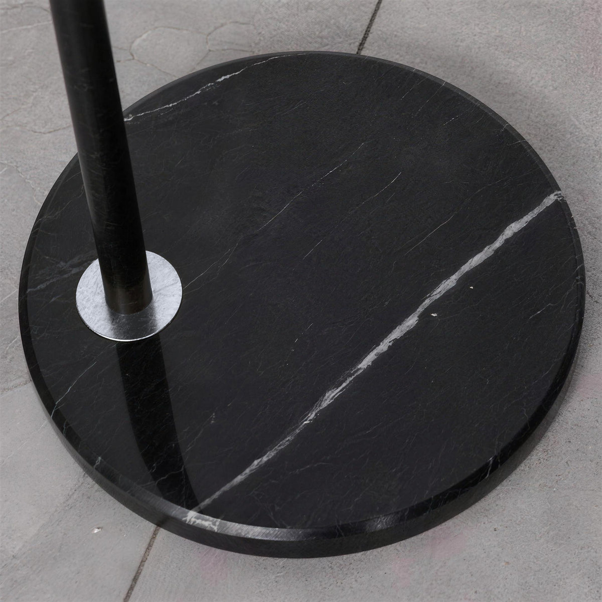 Black marble round base of a floor lamp with a chrome ring around the pole