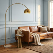 Gold arc floor lamp with marble base and dome shade in a bright living room