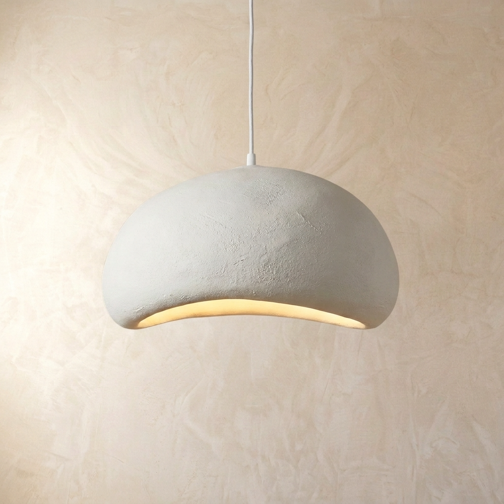 Modern viwa white resin Wabi-Sabi pendant light with an asymmetrical design hanging against a textured wall