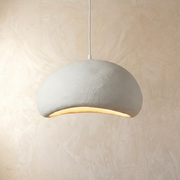 Modern viwa white resin Wabi-Sabi pendant light with an asymmetrical design hanging against a textured wall