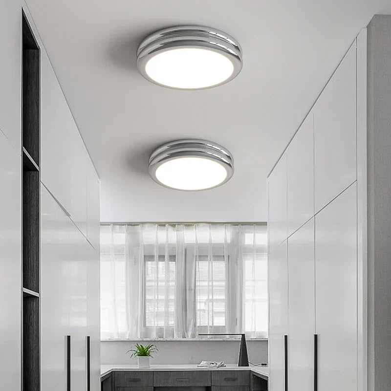 Chrome double-ring LED vyter ceiling lamps adding a sleek, modern touch to a white corridor