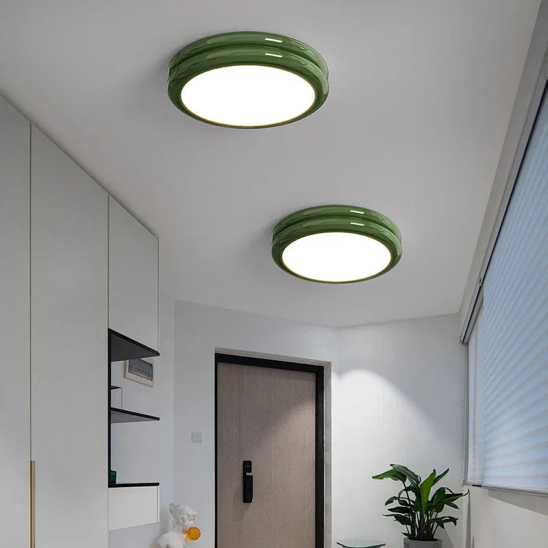 Two green glossy metal flush mount vyter ceiling lights installed in a minimalist white entryway