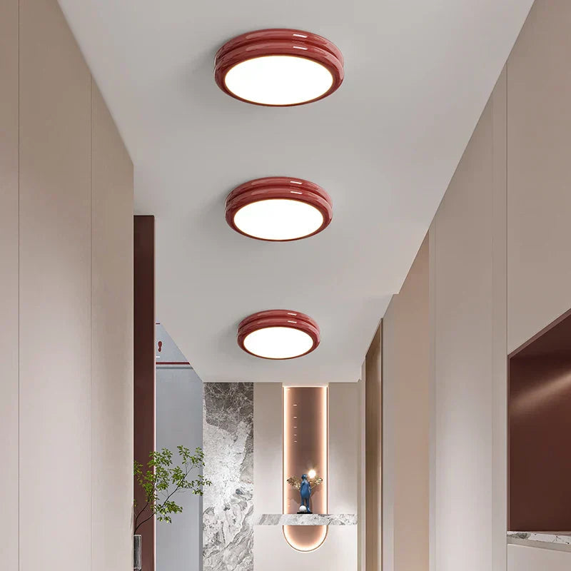 Three vibrant red stepped-ring flush mount vyter lights arranged in a sequence down a long corridor
