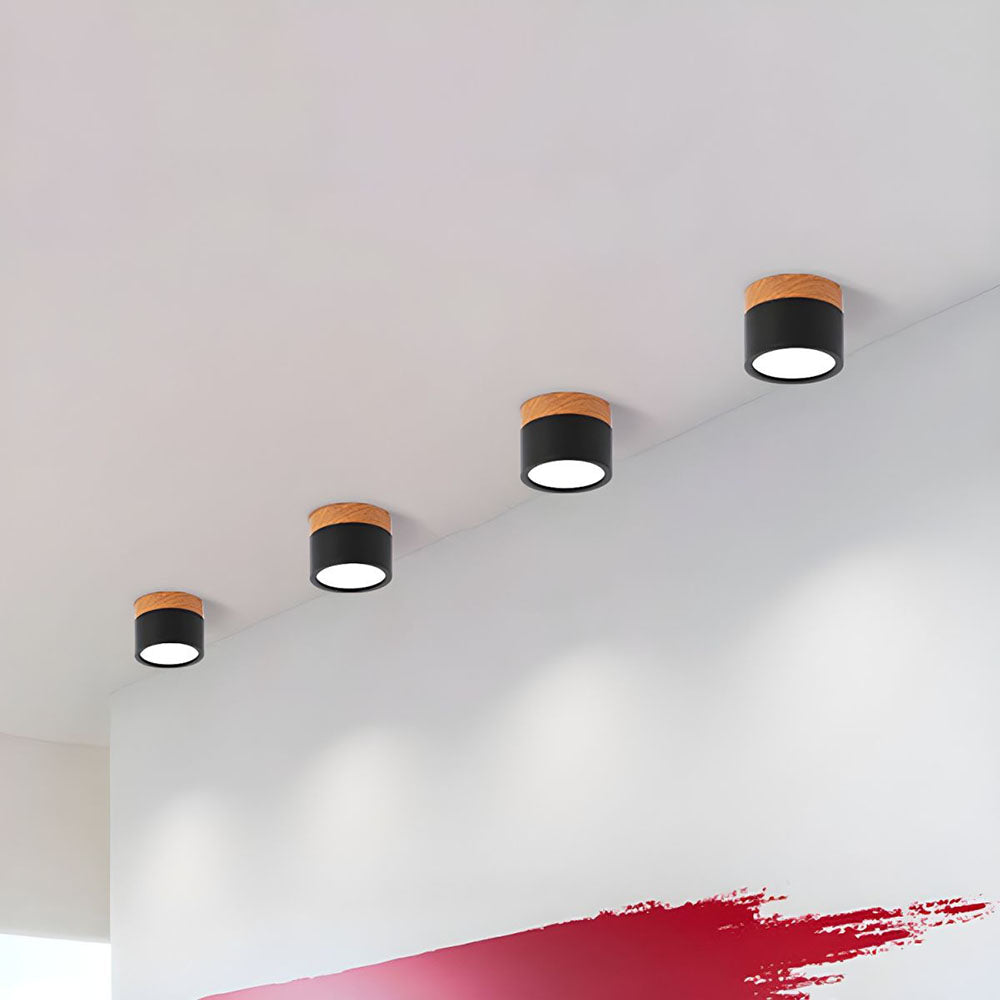 Row of black cylinder flush vytri ceiling lights acting as wall accent lighting