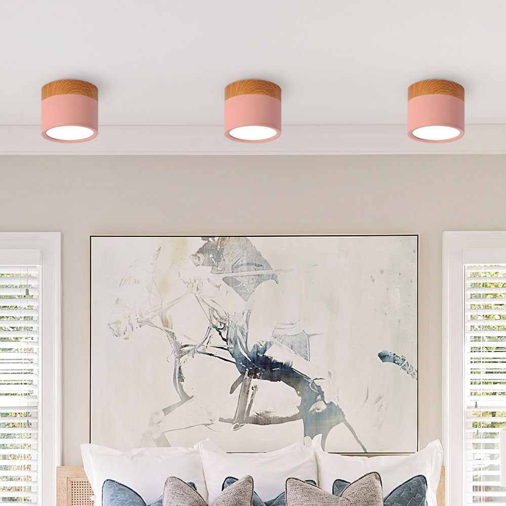 Row of soft pink cylinder flush vytri ceiling lights installed above a bed
