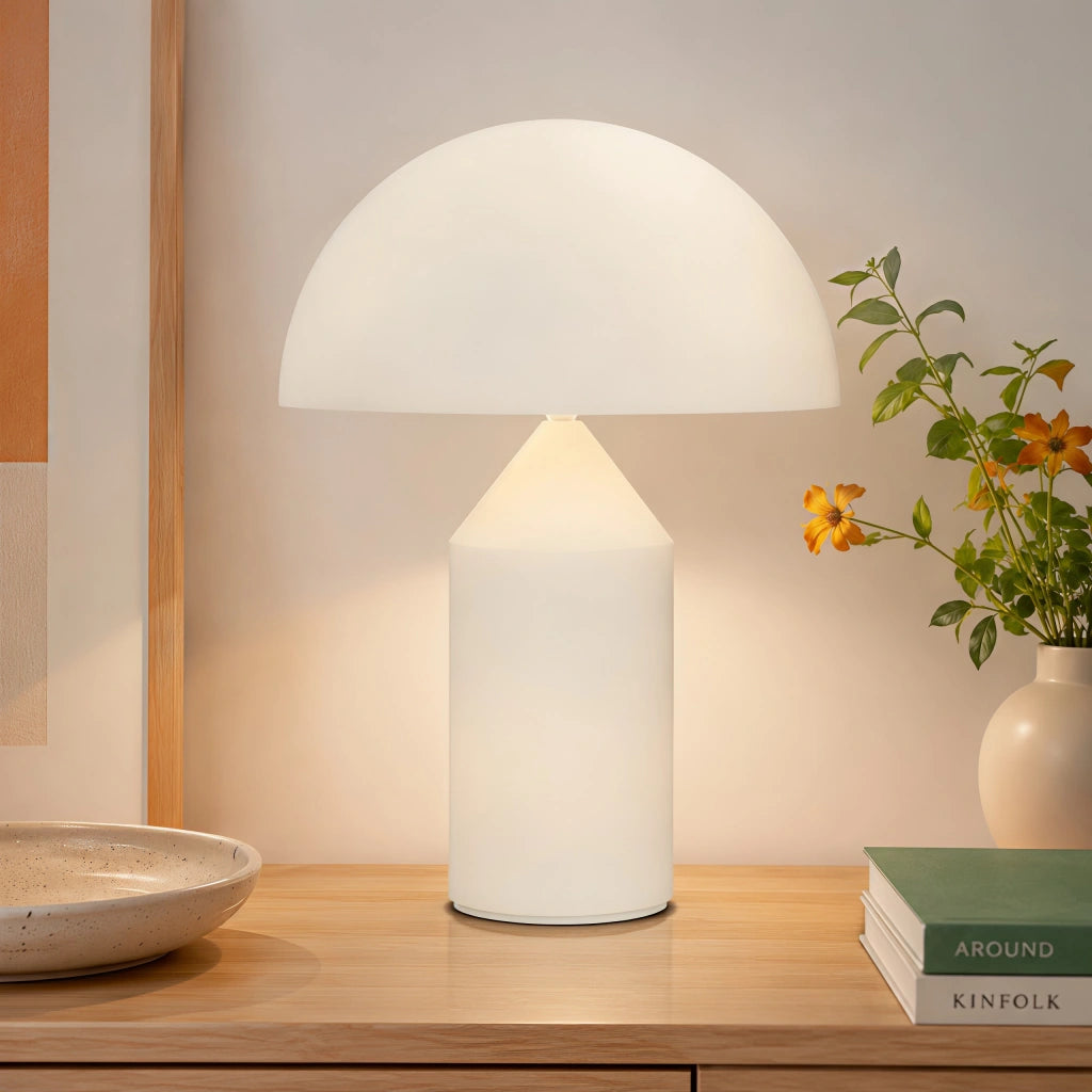 White mid-century wesk dome lamp providing warm ambient light on a rustic wooden desk