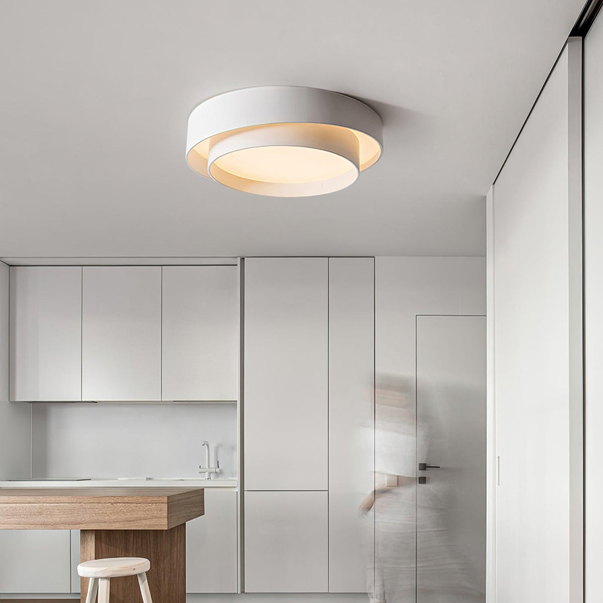 Modern wlip white concentric ring ceiling light illuminating a bright, minimalist white kitchen space