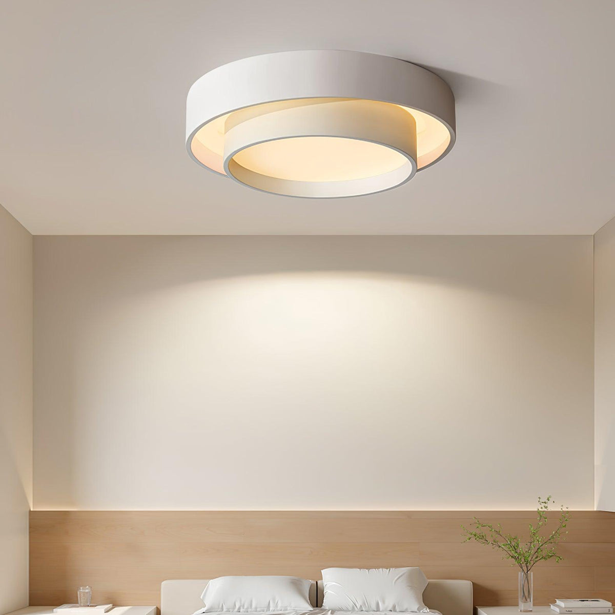 White wlip double-ring LED flush mount fixture casting a warm ambient glow above a modern bed