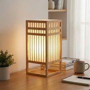 Xevlu Japandi wabi-sabi bamboo shoji table lamp glowing on a wood desk with plant and notebook