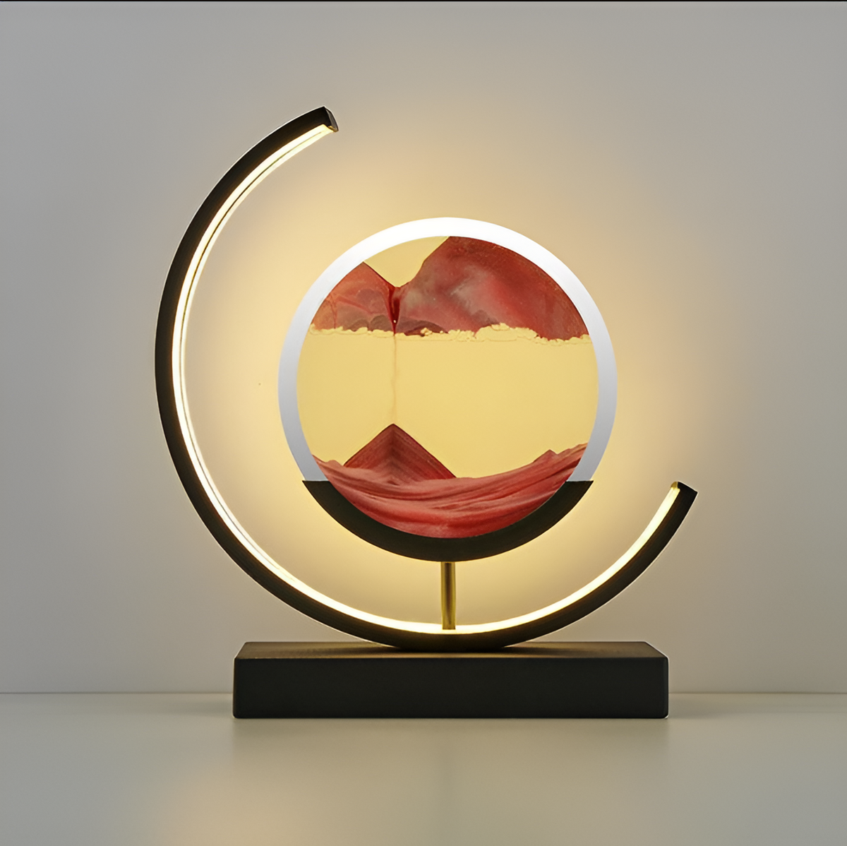 Front view of the youj black circular LED table lamp showcasing flowing orange sand art