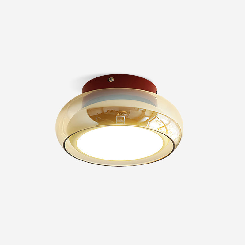 Amber tinted glass dome zuba lamp with a red metal base glowing against a plain ceiling