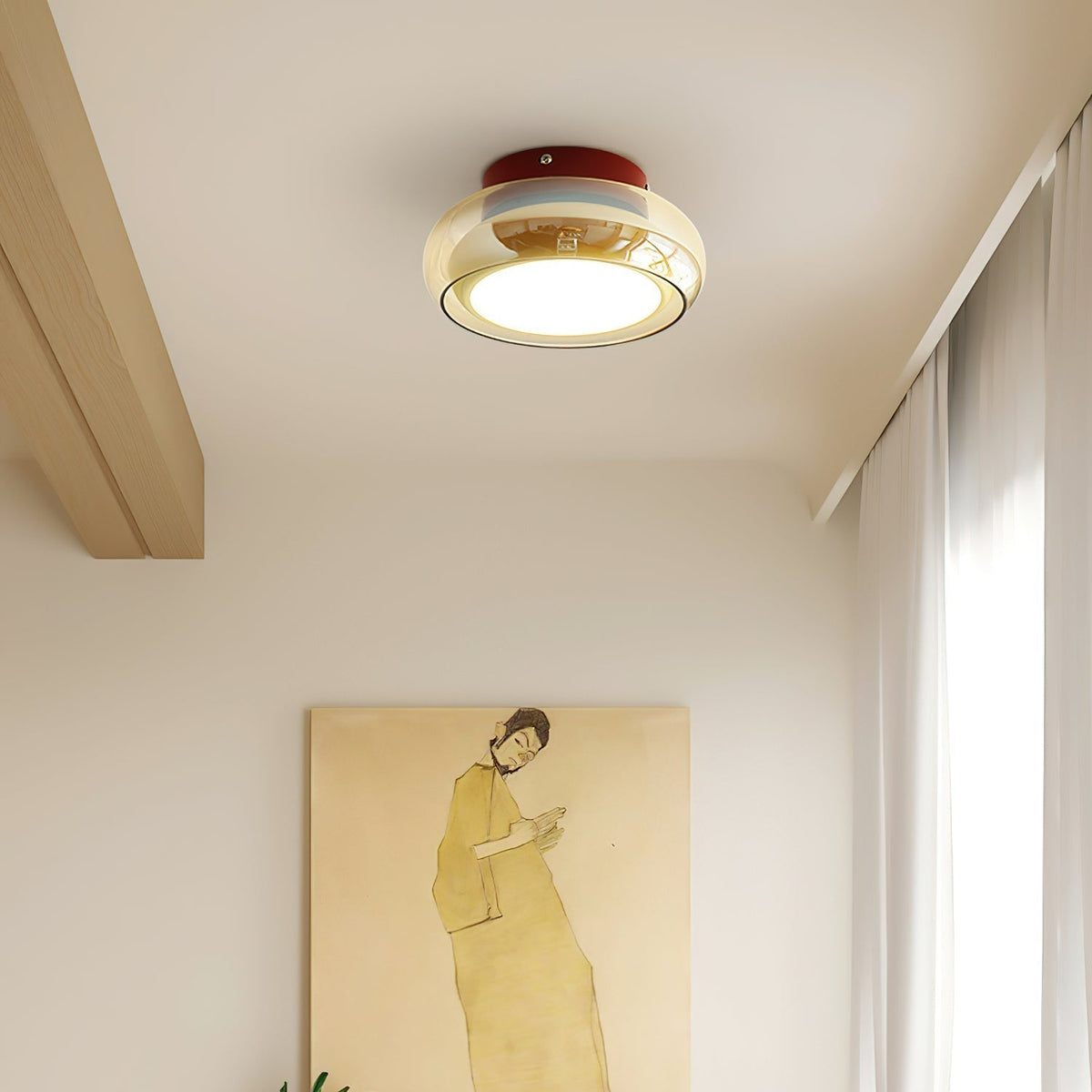 Red base and amber glass flush mount zuba ceiling light providing ambient lighting above a painting